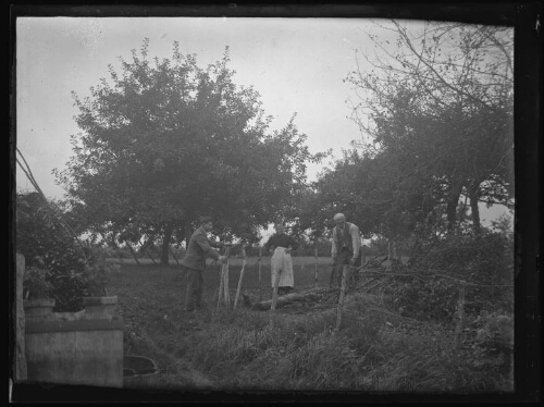 Marc Bry avec ses grands-parents dans le jardin de leur maison au Gué à Essay ; son grand-père coupe du bois