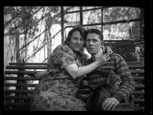 Portrait en buste d'un couple assis sur un banc avec un chat assis sur les jambes de l'homme