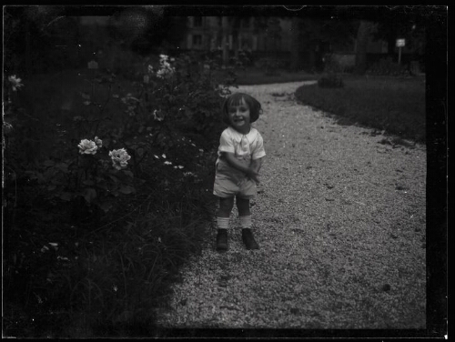 Portrait en pied d'une fillette debout dans une allée de jardin
