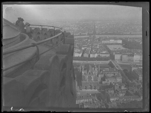 Lyon (Rhône) : vue panoramique sur la cathédrale Saint-Jean Baptiste et la place Bellecourt de Lyon prise du haut de la basilique Notre-Dame de Fourvière ; un couple avec un enfant observent le panorama du haut de la basilique