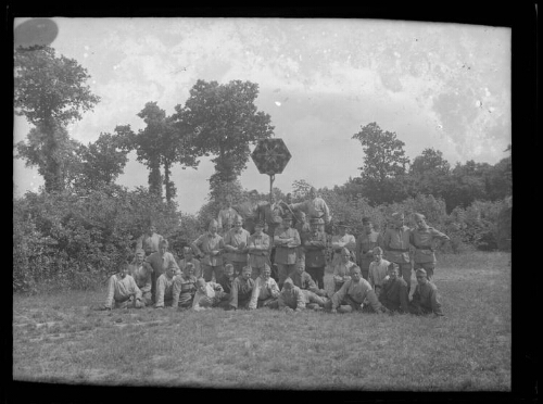 Militaires : des hommes en habit militaire posent alignés, sur trois rangées, dehors devant un détecteur acoustique ; les hommes devant sont assis ; arbres en arrière-plan