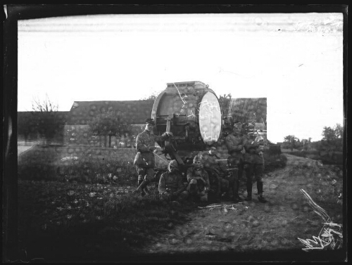 Militaires : six hommes en habit militaire posent autour d'un projecteur pour l'atterrissage des avions sur des aérodromes ; l'un d'entre eux porte un képi, un autre tient un chien dans ses bras ; hangar en arrière plan