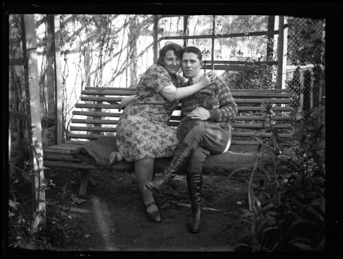 Portrait en pied d'un couple assis sur un banc recouvert d'un plaid avec un chat assis sur les jambes de l'homme