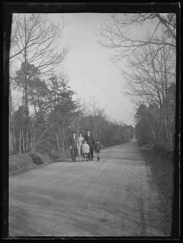 Groupe de personnes : un couple, un homme et deux enfants debout sur une route de forêt