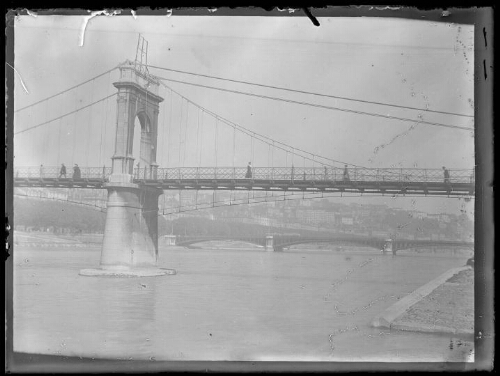 Lyon (Rhône) ?: passerelle Masaryk ? ; plusieurs personnes se déplacent sur le pont suspendu ; un autre pont et la ville en arrière-plan