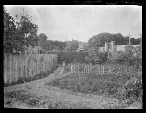 Paysage : jardin avec couple en haut d'un muret, portail en arrière-plan