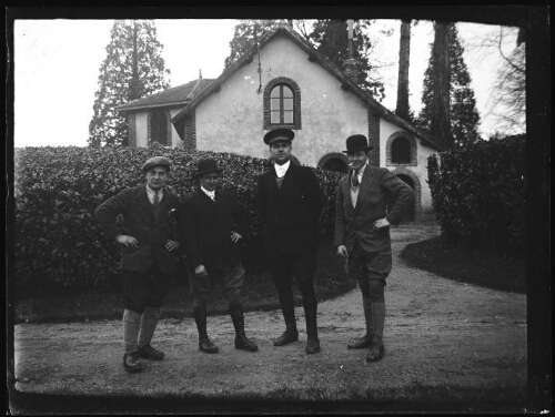 Bursard (Orne) : quatre hommes debout devant les remises aux voitures du Haras du Bois Roussel
