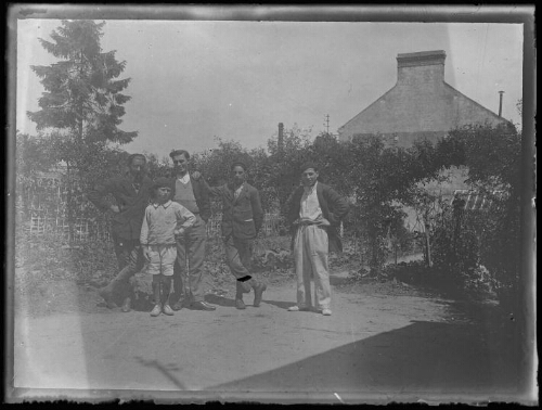 Portrait de groupe : Marc Bry avec trois amis et un enfant debout devant un jardin