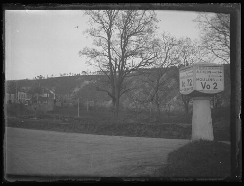 Moulins-le-Carbonnel (Sarthe) : carrefour de route avec une "Borne Michelin" indiquant " Alençon - 17 ; 6 - Moulins le C ; Vo 2 " et " 5 - Souge le Ganelon ; Ic 72 ; 7 - Gesvres ", le 11 mars 1933