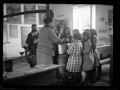 Scène d'écoliers: les élèves présentent leur bol à l'institutrice dans la salle de classe