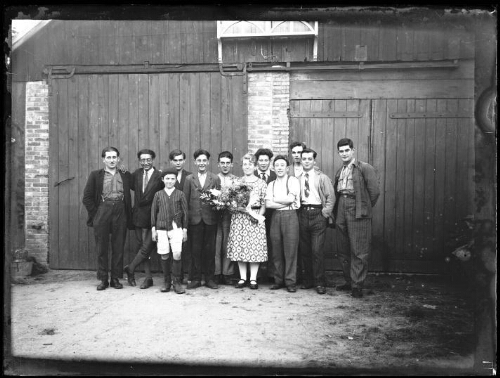 Portrait de groupe : dix hommes, dont Marc Bry, sa mère Juliette, et un enfant posent devant une grange